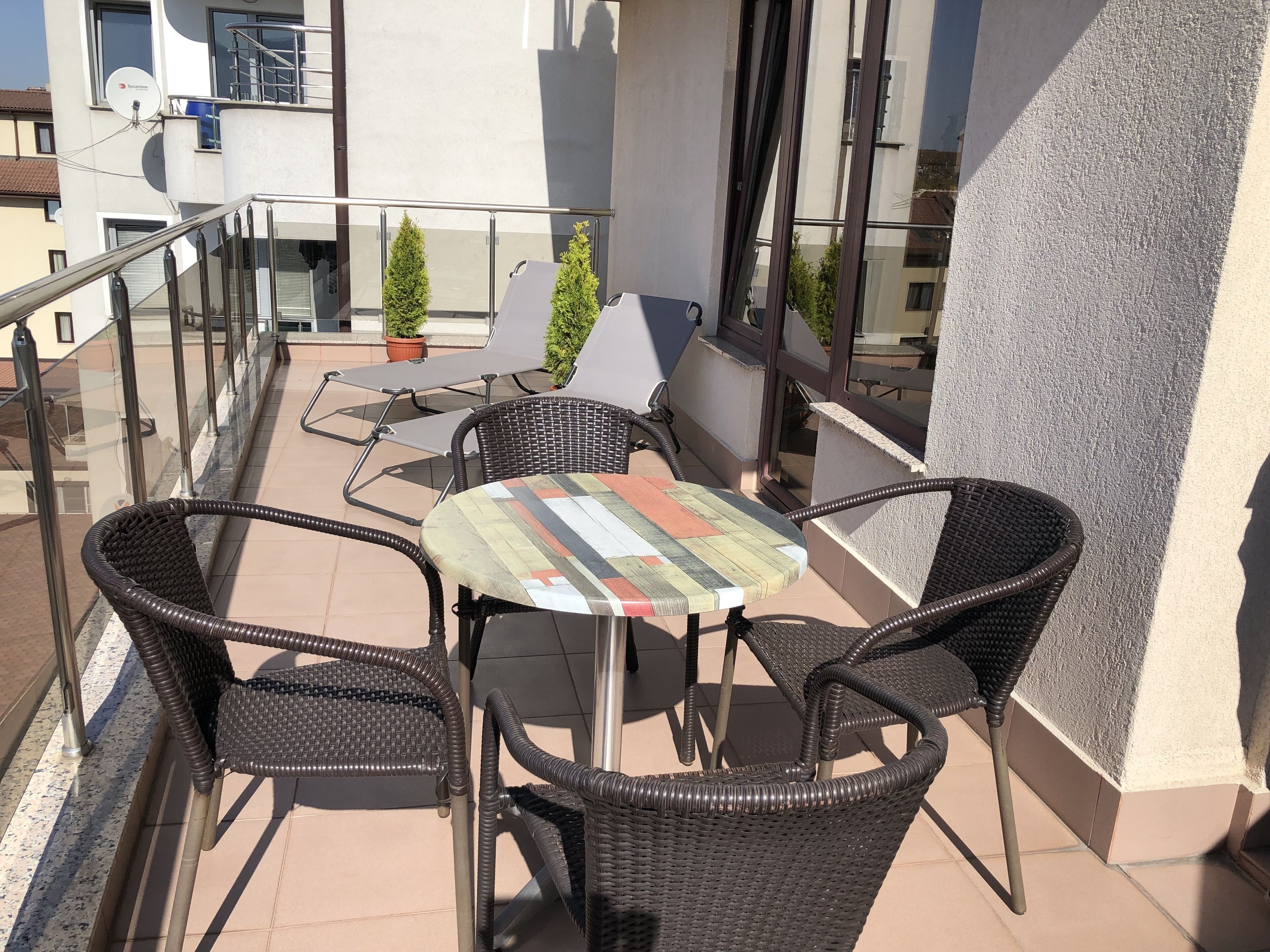 A balcony with wicker chairs, a small round table, and potted plants.