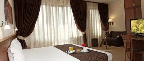 Una habitación de hotel con cama, una mesa de comedor, un televisor y un escritorio.