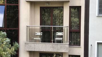 Un edificio de varios pisos con un balcón que tiene dos sillas blancas.