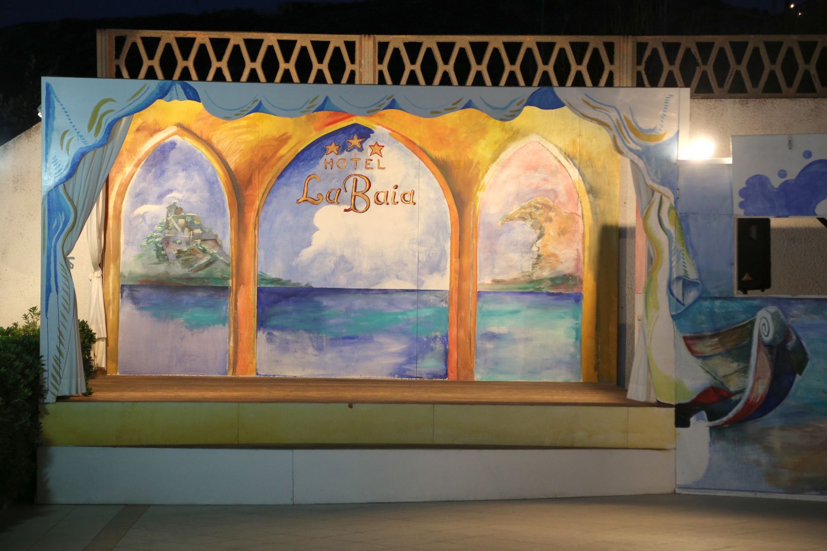 Ein Wandgemälde zeigt eine Strandansicht mit der Aufschrift 'Hotel La Baida' an einer Gebäudefassade.
