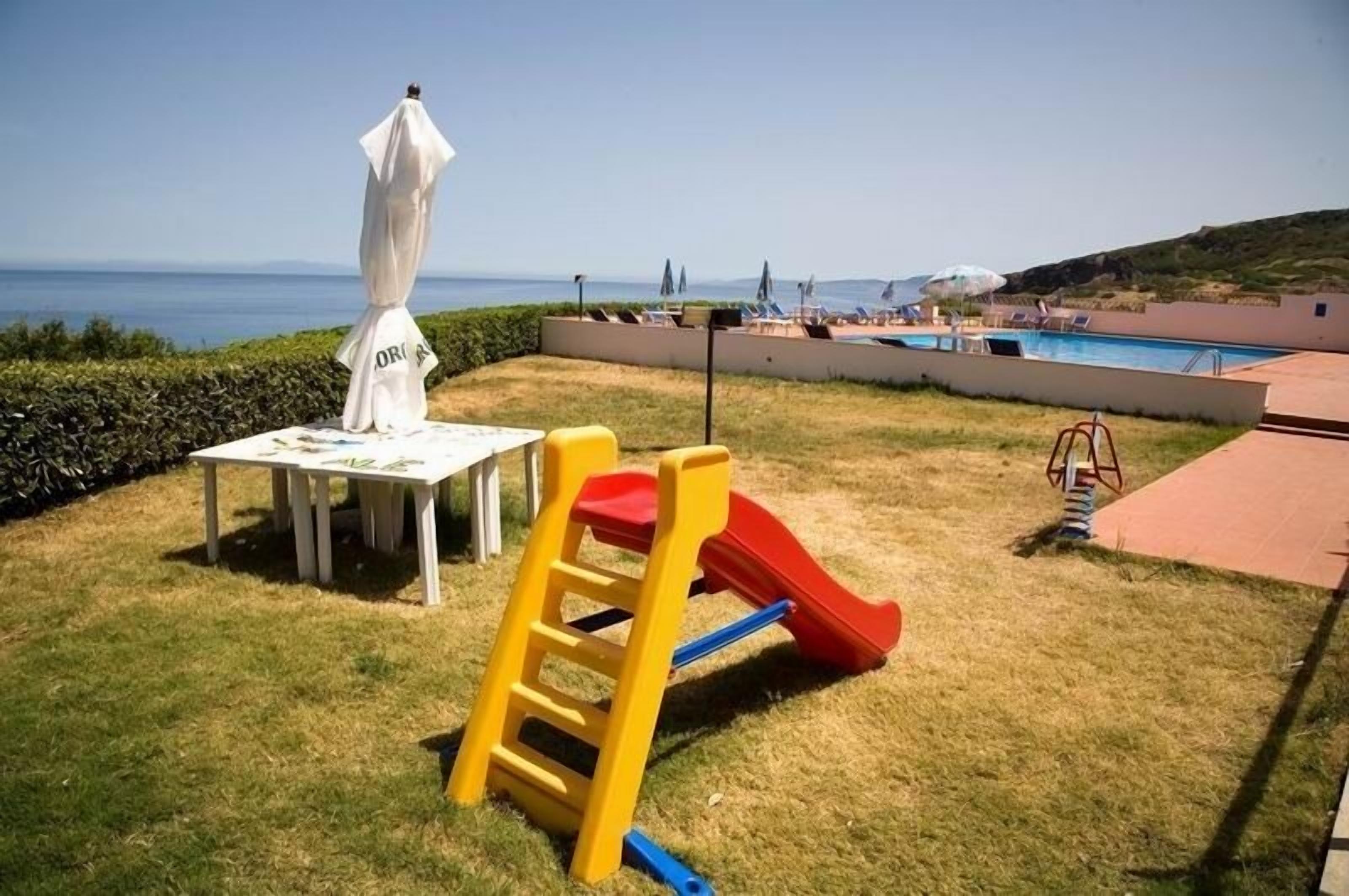 A children's play area with a slide and a table with a white umbrella.