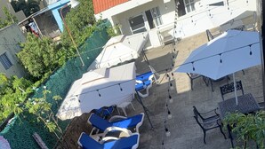 A rooftop pool area with lounge chairs, umbrellas, and string lights.