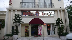 A hotel with a balcony, a sign for a bar and lounge, and a sign for a restaurant.