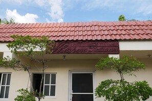 A building with a red-tiled roof and a sign that reads "Thai Food Restaurant." - Hotel Luis V (Santo Domingo)