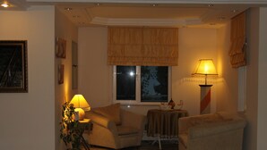 A cozy living room with two armchairs, a small table, a lamp, and a window with a view of the night sky. - Villa Granada Hotel (Konyaalti)