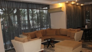 A modern living room with a sectional sofa, a small round table, and a coffee table. - Villa Granada Hotel (Konyaalti)