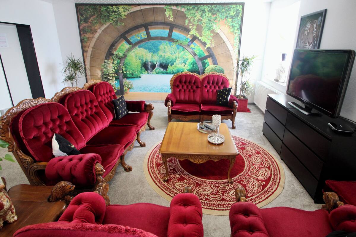 Un salon luxueux avec des canapés rouges, une table basse en bois et un grand téléviseur.