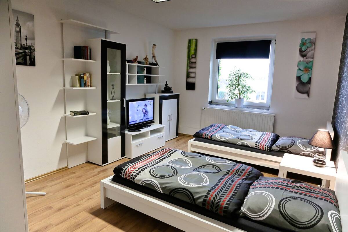 Une chambre à coucher moderne, avec un lit, une télévision et une bibliothèque.