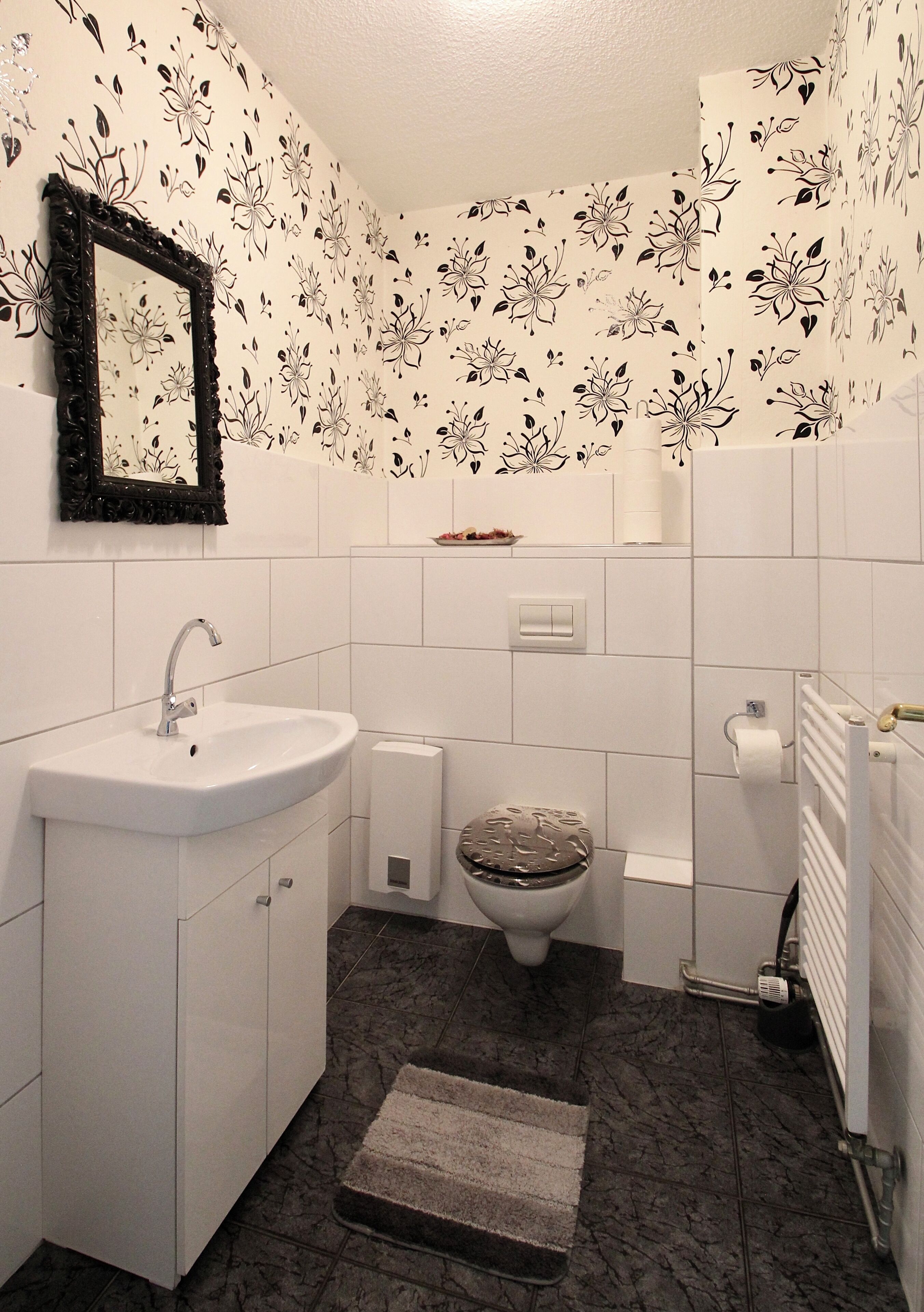 A bathroom with a white sink, toilet, and a mirror.