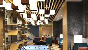 A pool table with balls, a sofa, and a chair in a room with a patterned floor. - Aloft Dalian (Dalian)