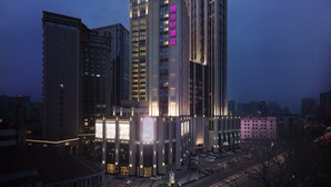 A high-rise hotel with illuminated signage and multiple floors. - Aloft Dalian (Dalian)