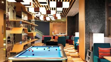 Ein Billardtisch mit Kugeln, eine Couch und eine Treppe in einer modernen Lobby.