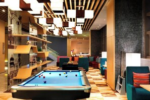 A pool table with balls, a sofa, and a staircase in a modern lobby. - Aloft Dalian (Dalian)