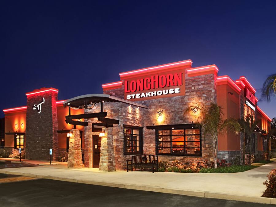 A steakhouse with a brick facade and red neon signage.