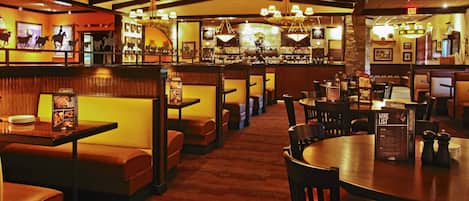 A restaurant with booths and tables, a bar area, and a menu stand.