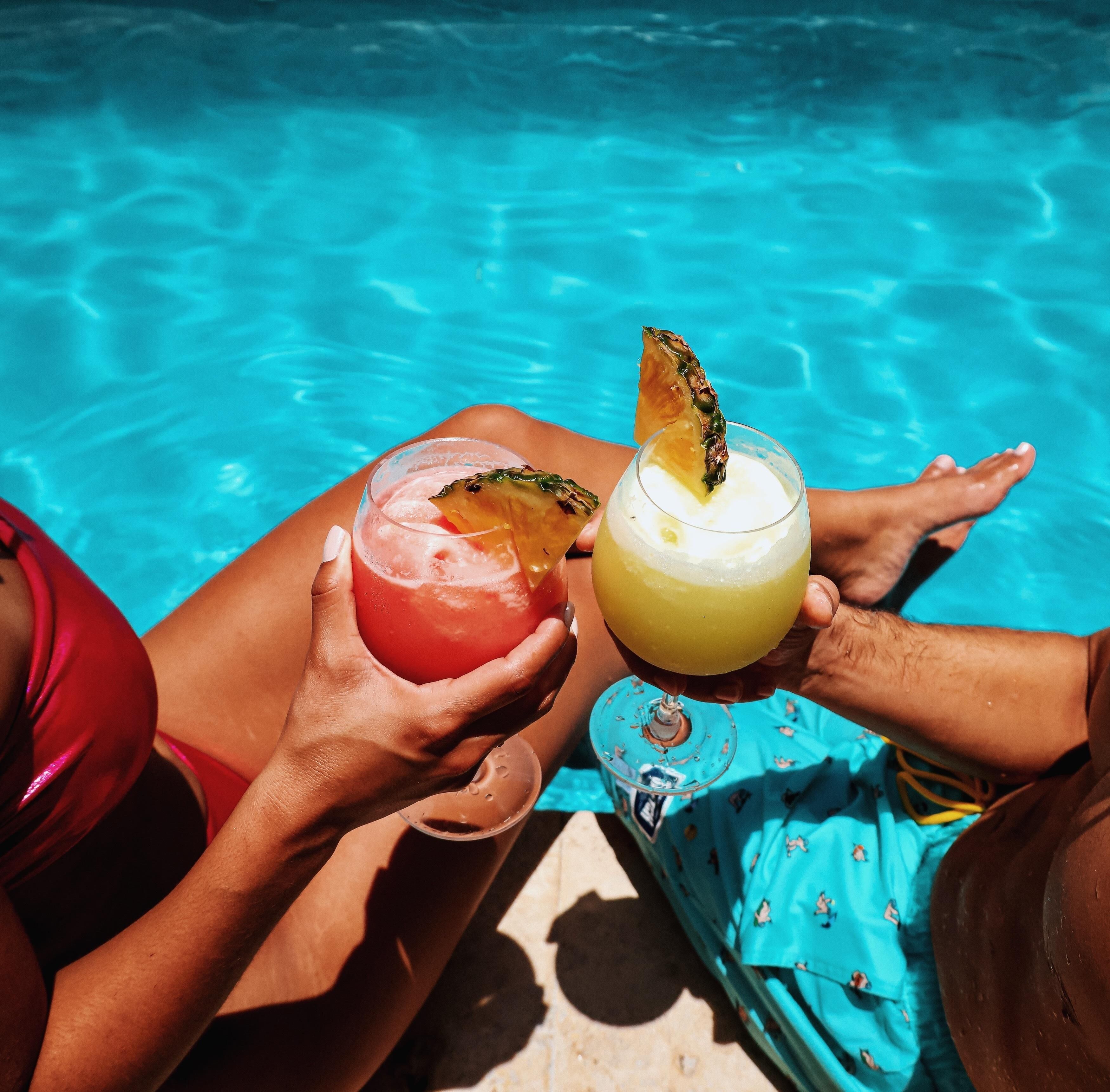 To personer holder drinks ved en pool.