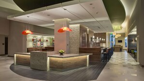 A modern hotel lobby with a reception desk, seating area, and a check-in counter. - Hyatt Place Manati (Manati)