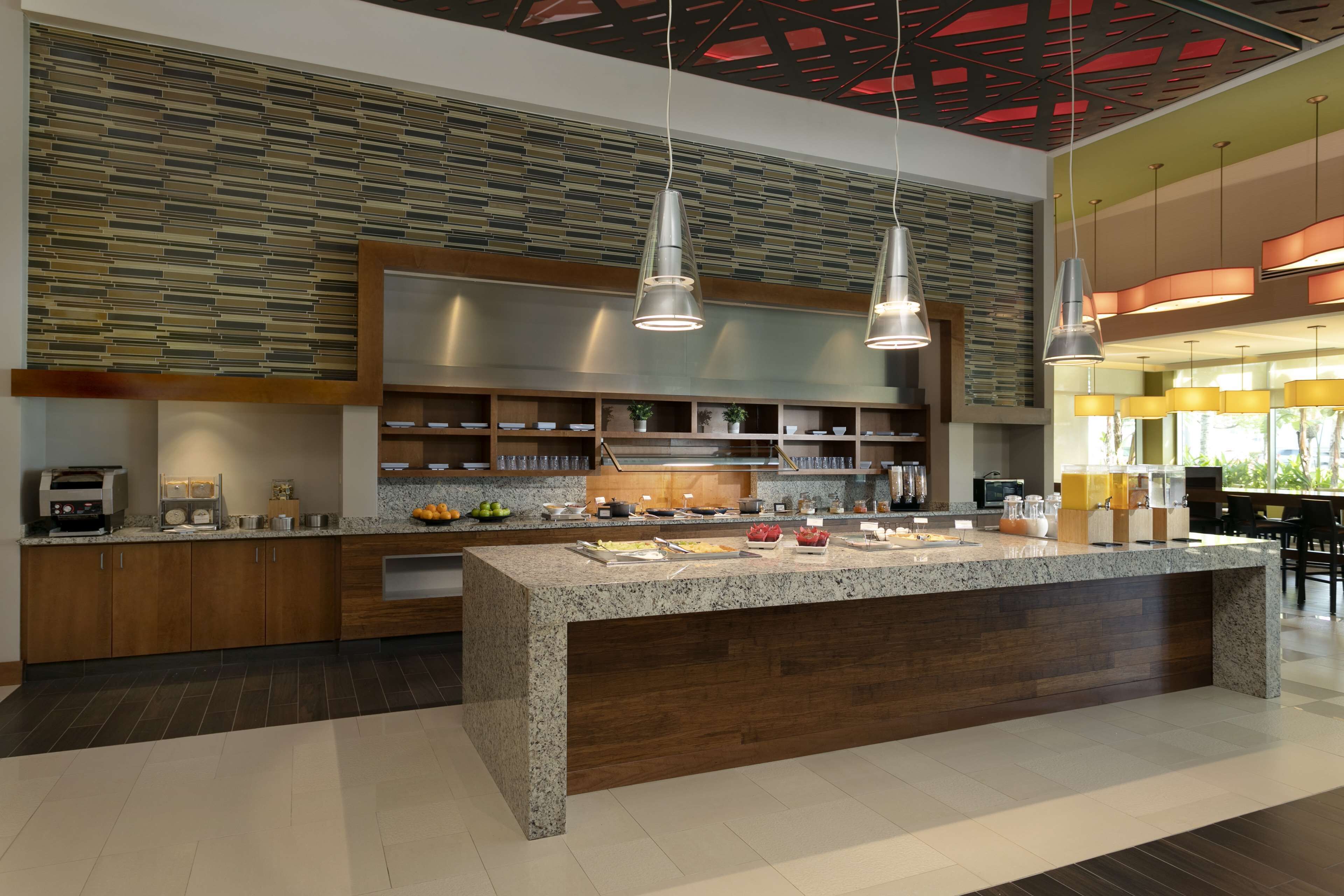 A modern kitchen with granite countertops, wooden cabinets, and pendant lighting.