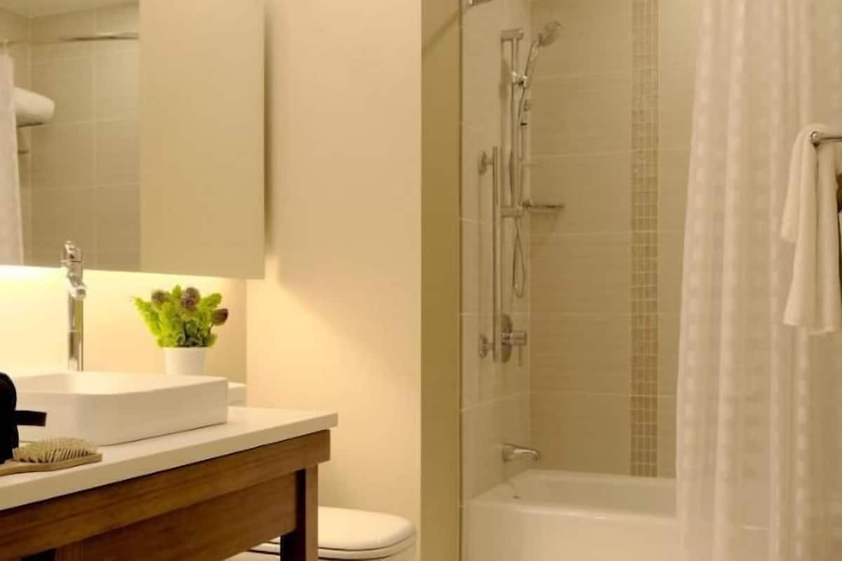 A bathroom with a sink, mirror, shower, and toilet.