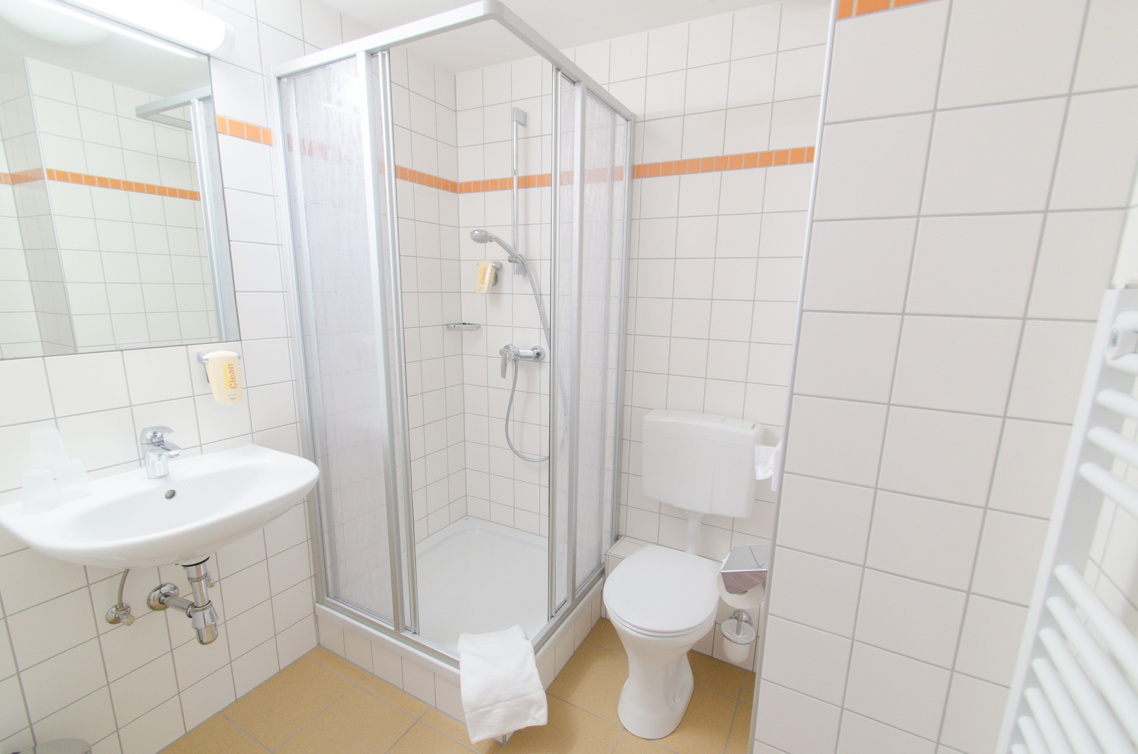 A bathroom with a glass-enclosed shower, a white sink, and a toilet.
