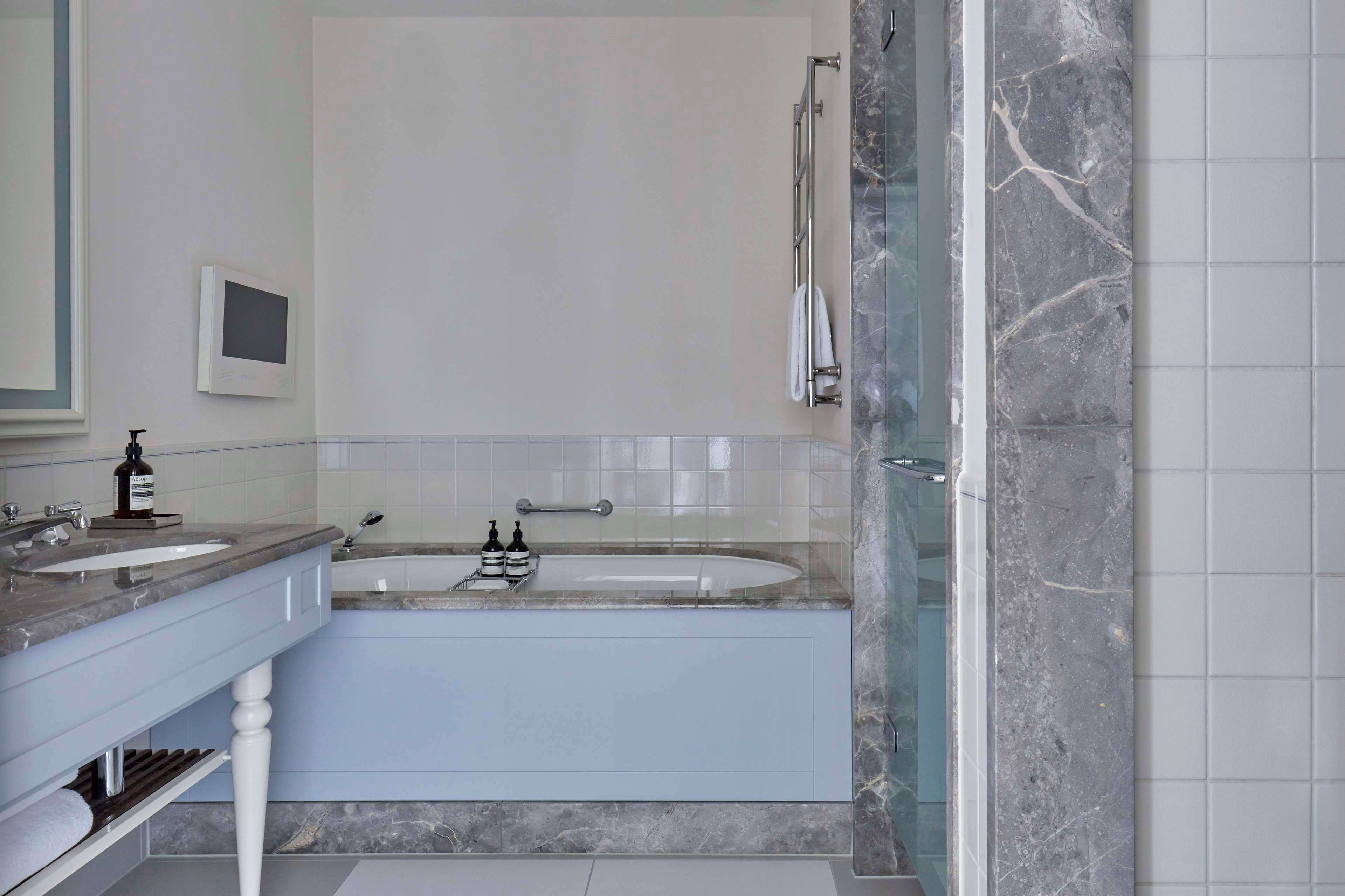 Un baño moderno con tocador doble, bañera y zona de ducha con mampara de vidrio.