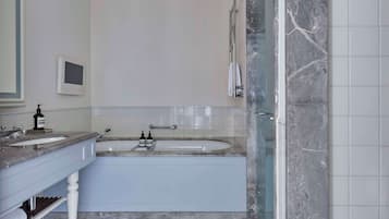 Un baño moderno con tocador doble, bañera y zona de ducha con mampara de vidrio.