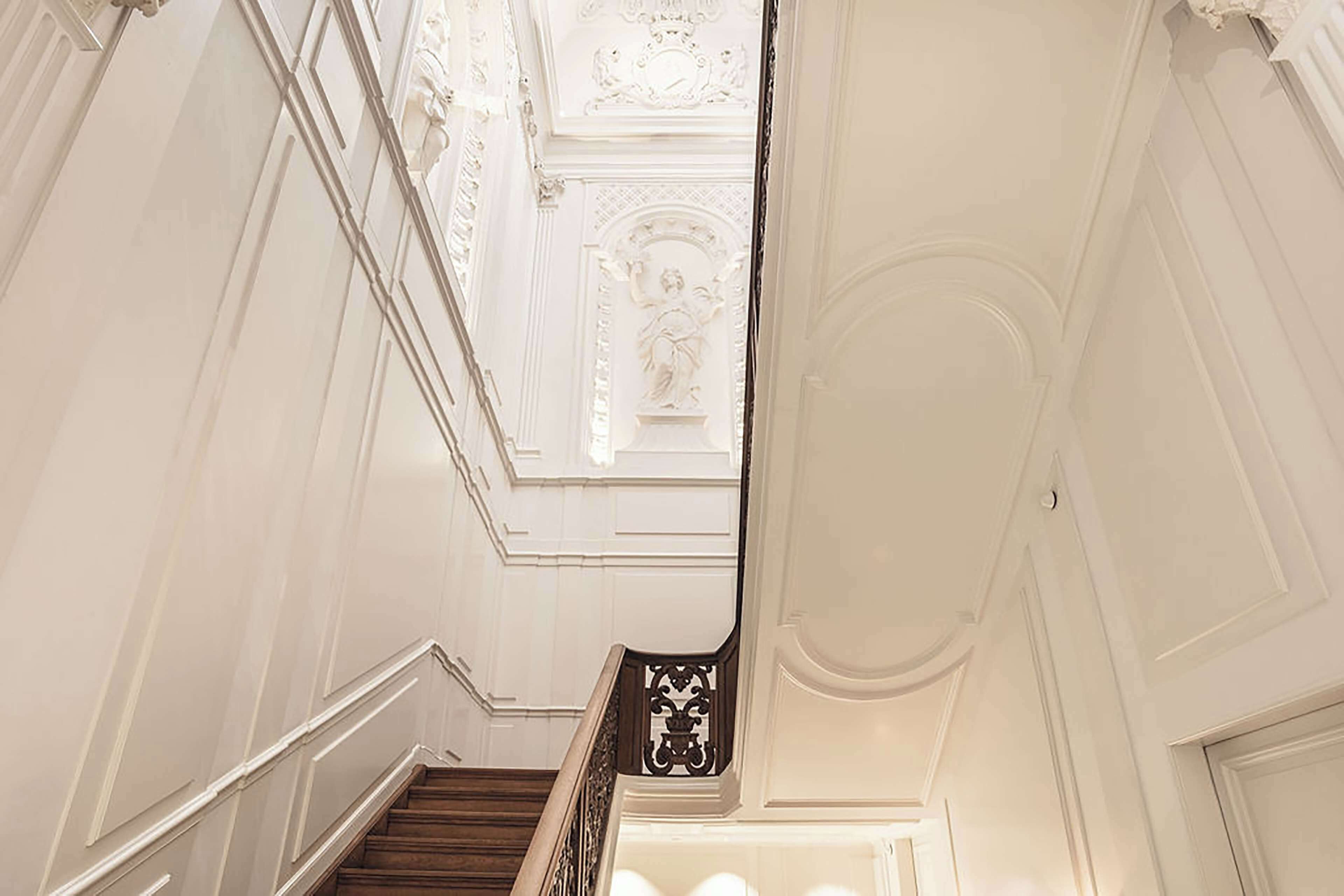 A grand staircase with ornate railings and detailed wall moldings.