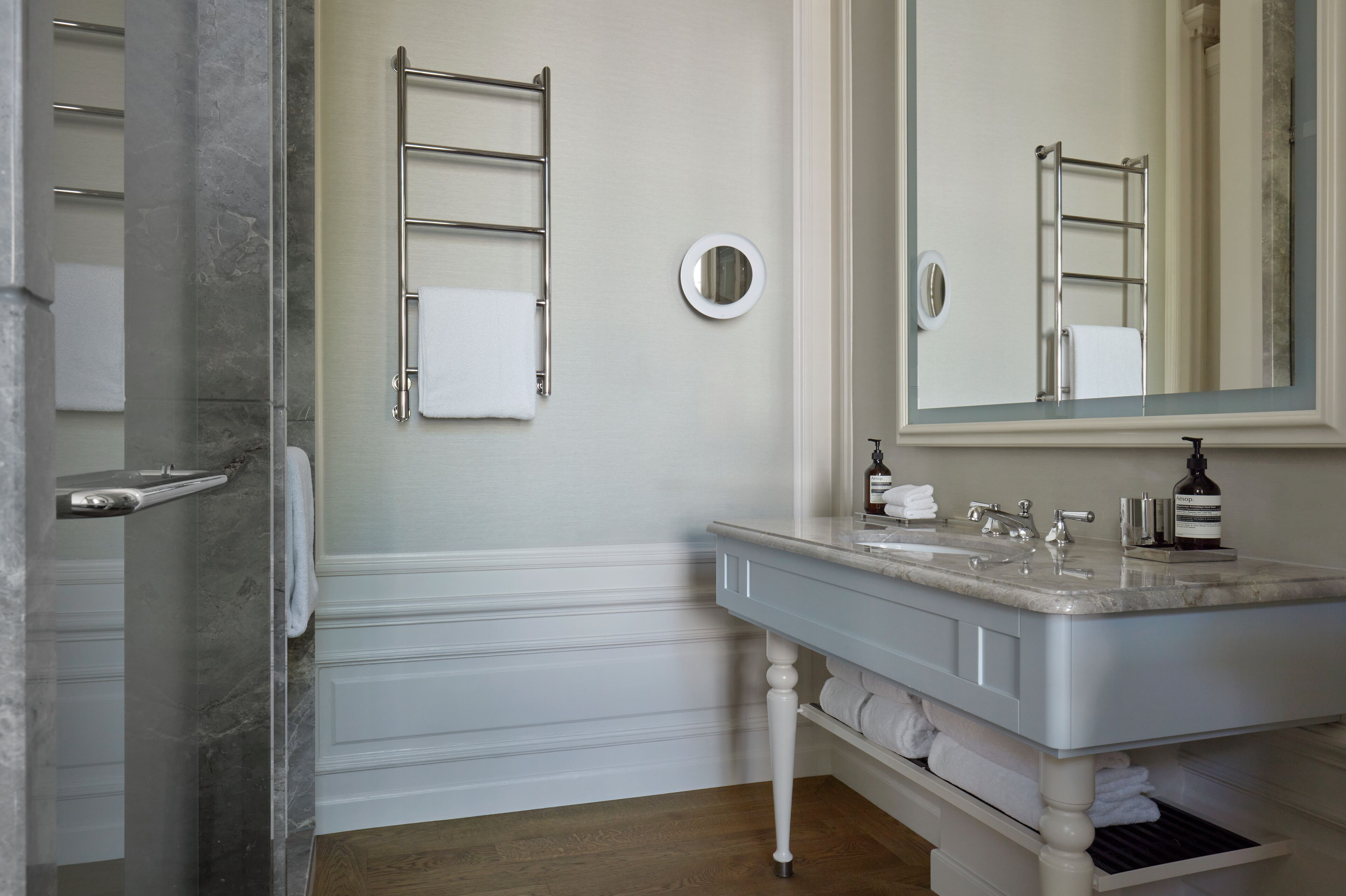 A bathroom with a marble sink, a mirror, a towel rack, and a shower area.