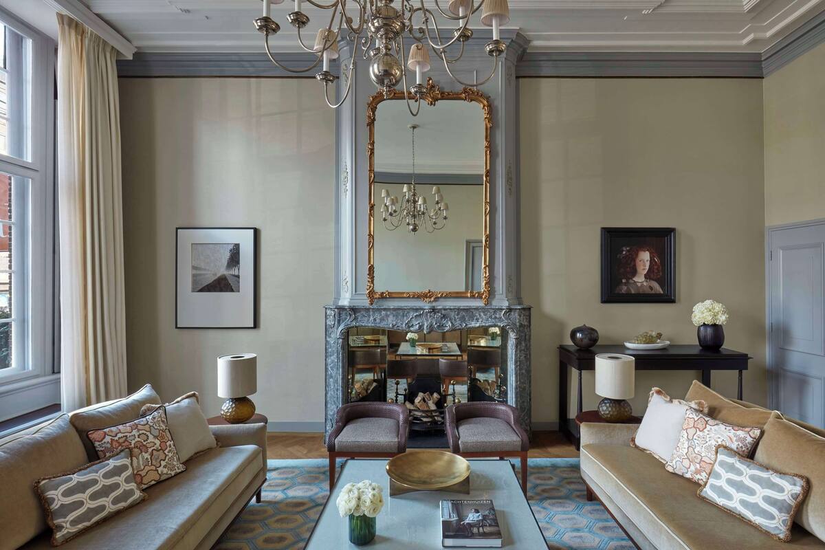 A living room with a fireplace, two sofas, a coffee table, and a chandelier.