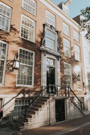 A multi-story building with a brick facade, large windows, and a central entrance with a staircase. - Waldorf Astoria Amsterdam (Amsterdam)