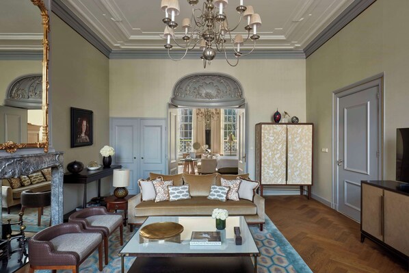 A spacious living room with a sofa, chairs, a coffee table, and a chandelier. - Waldorf Astoria Amsterdam (Amsterdam)
