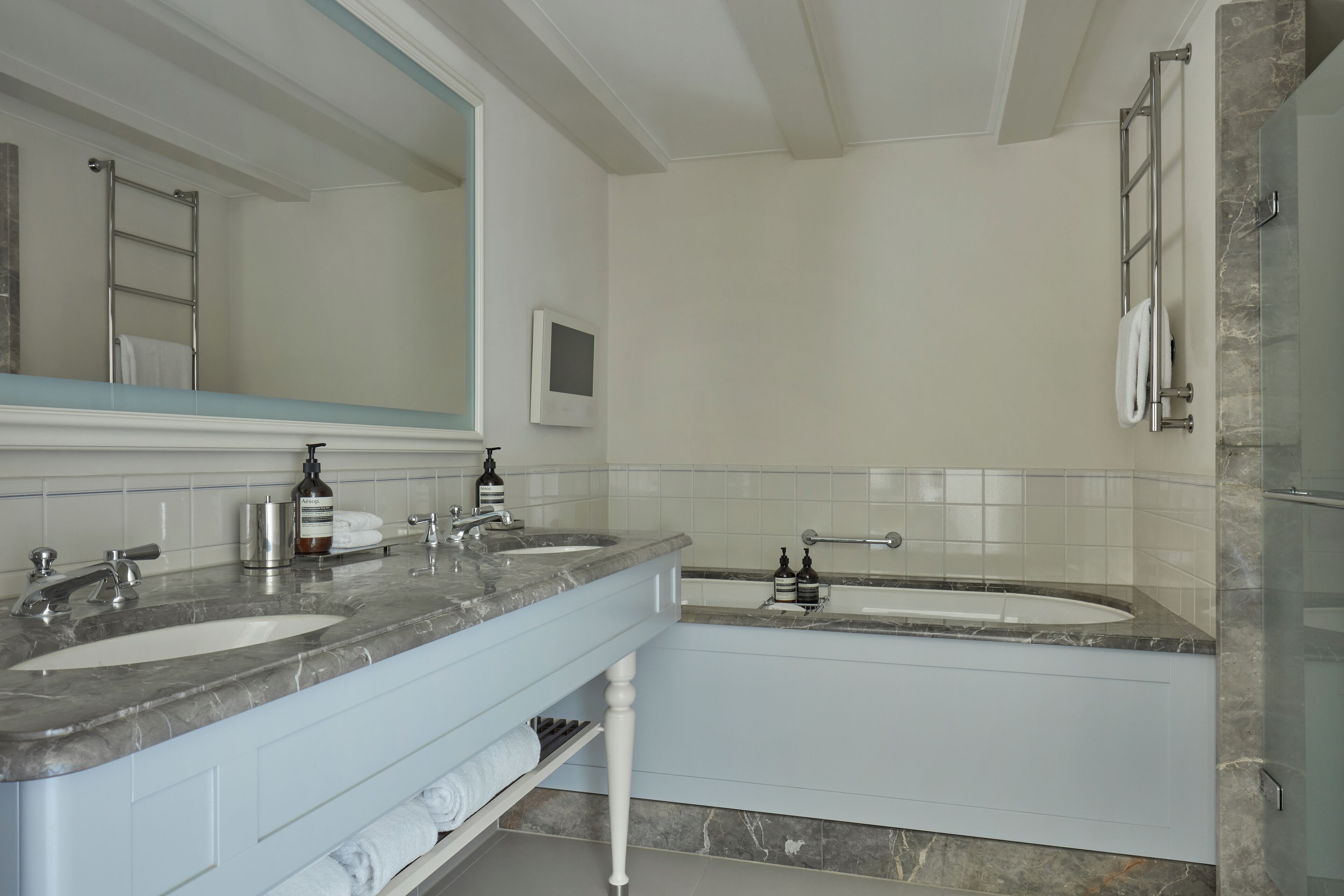 A modern bathroom with two sinks, a large mirror, and a glass shower enclosure.