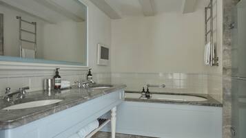A modern bathroom with two sinks, a large mirror, and a glass shower enclosure.