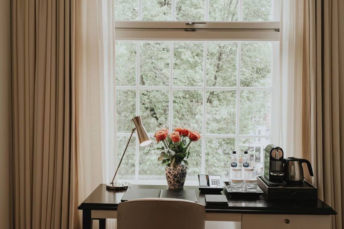 A room with a desk, chair, and a window with curtains.