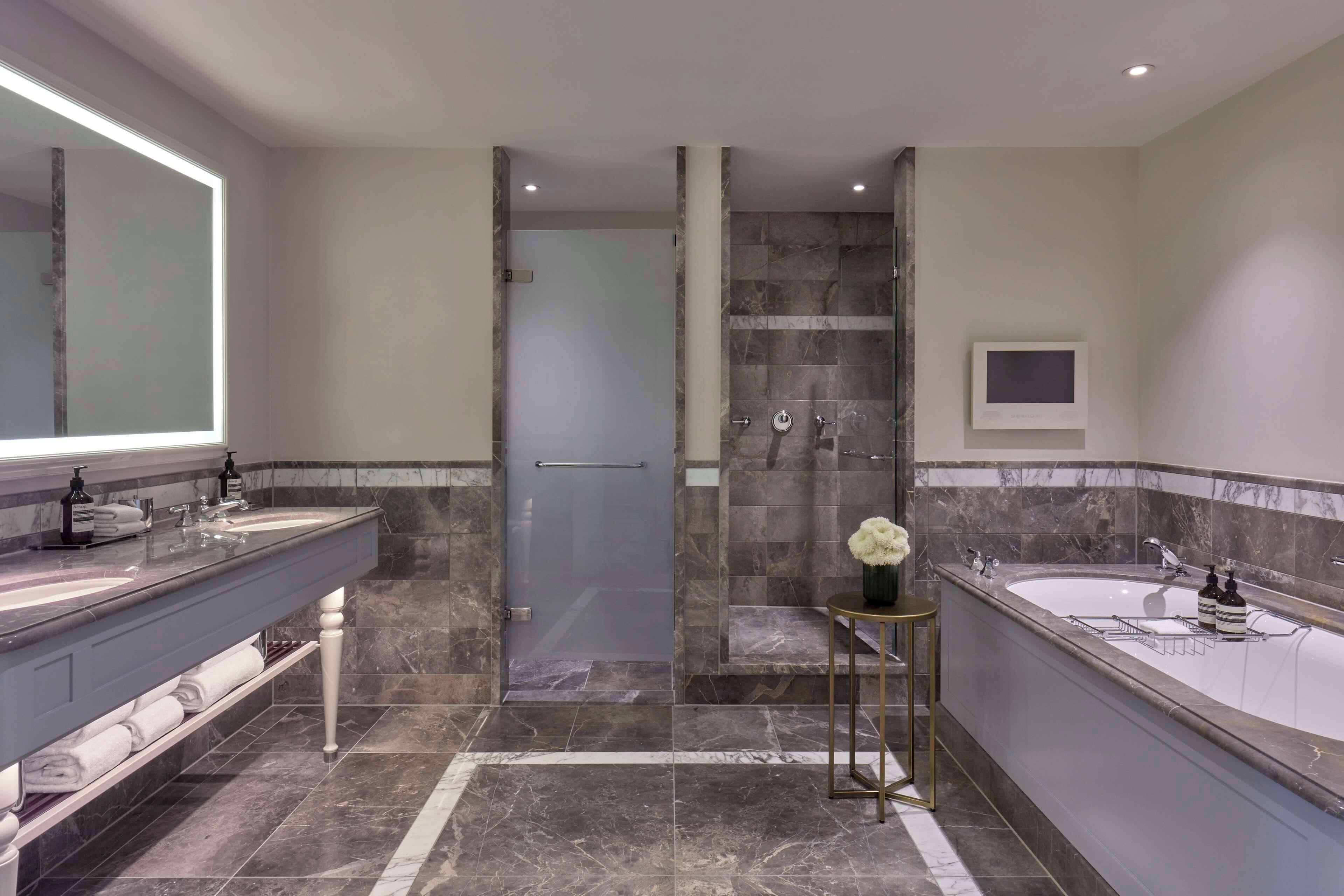 A modern bathroom with two sinks, a shower, and a vanity with a large mirror.