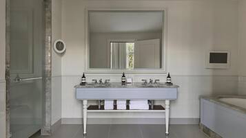 A modern bathroom with a double sink, a large mirror, a toilet, and a bathtub.