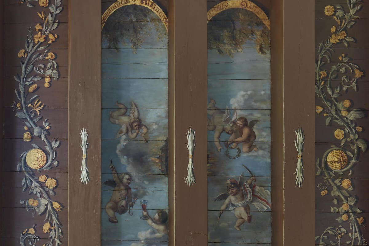 A ceiling with classical frescoes, cherubs, and floral motifs.