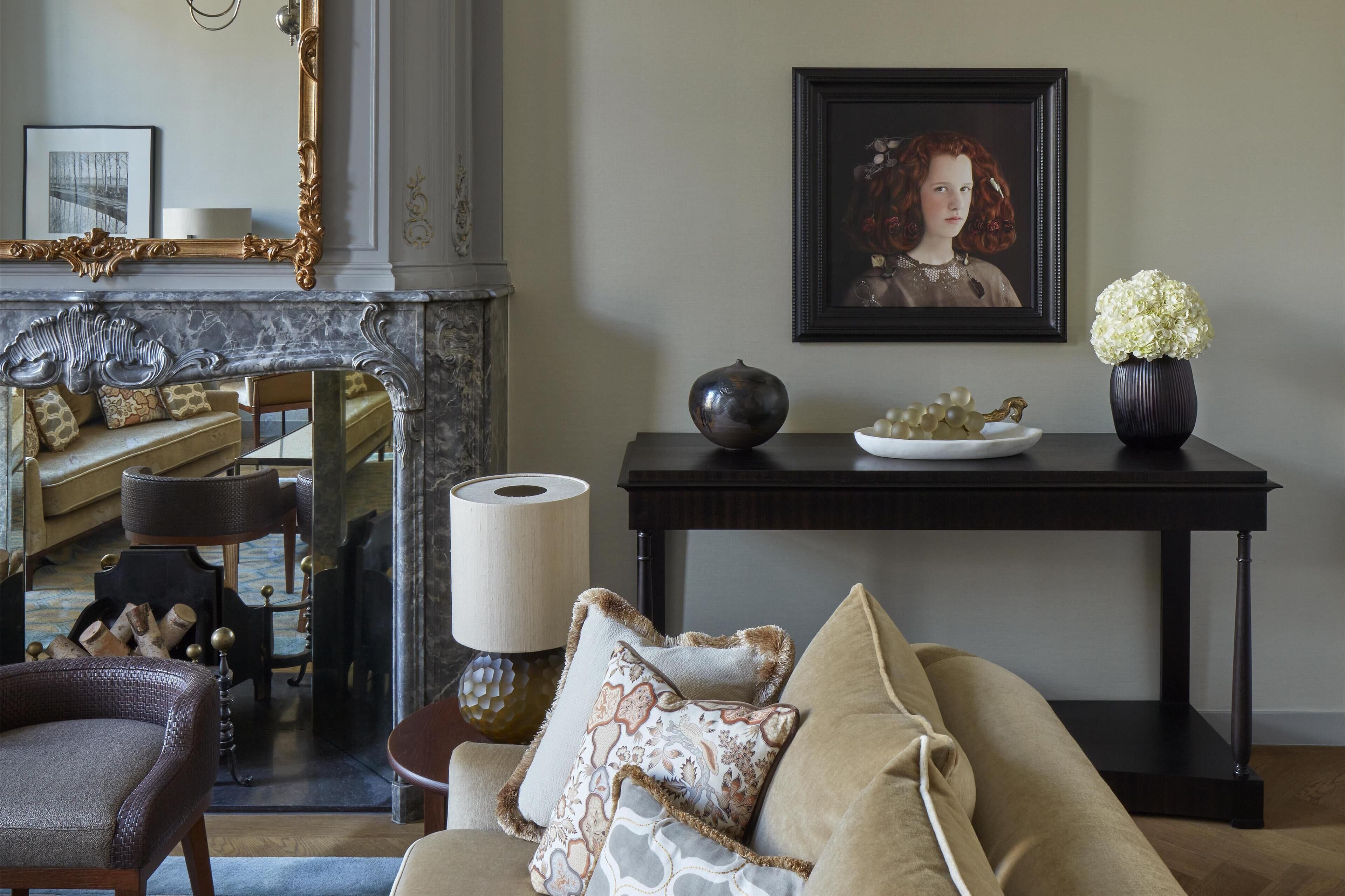 Un salon avec une cheminée, un canapé, une table agrémentée d’objets décoratifs et un portrait encadré accroché au mur.