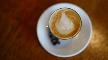 A glass of coffee with latte art on a white saucer.