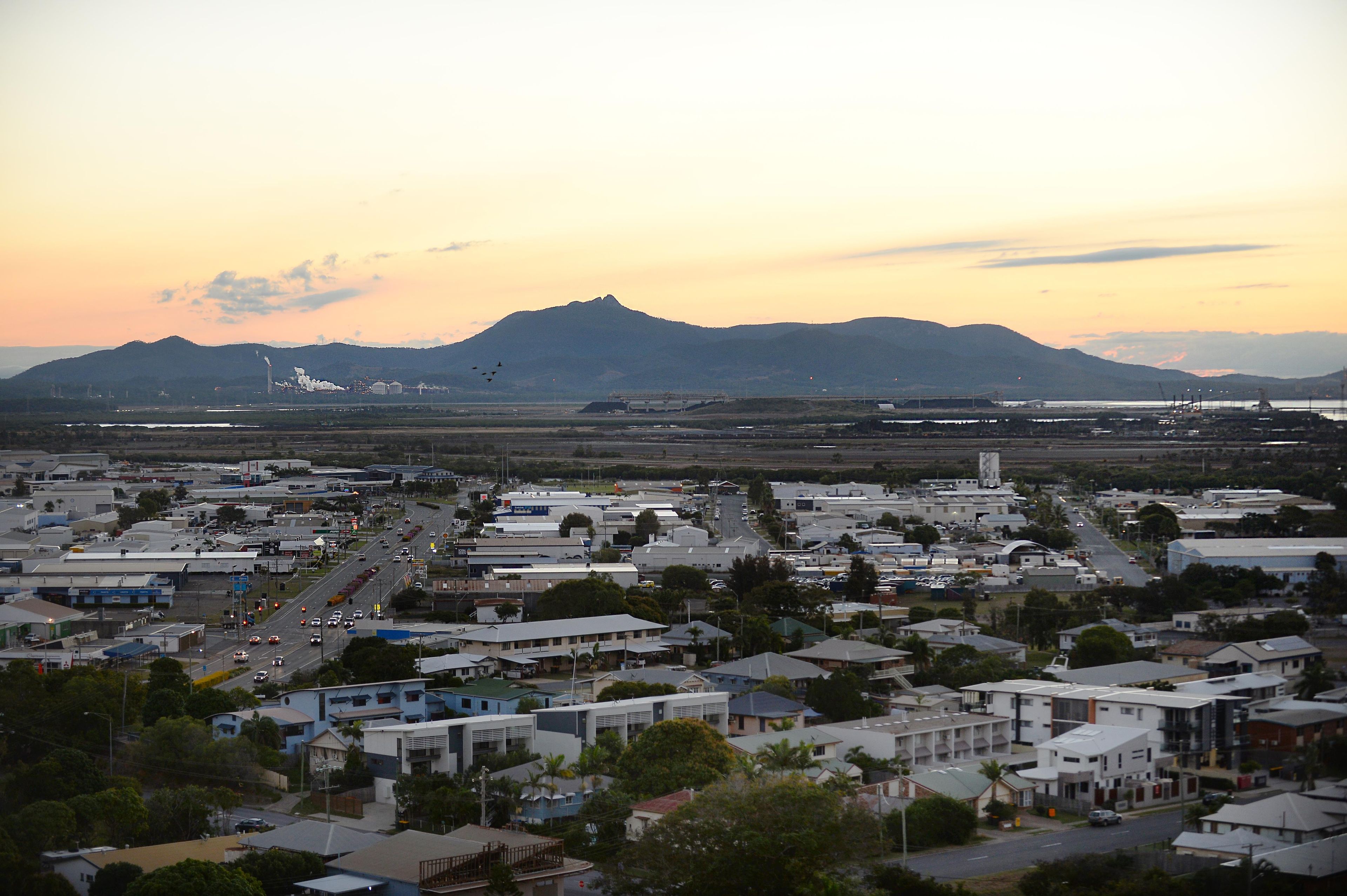 A cityscape with a mountain in the background, a highway, and various buildings.