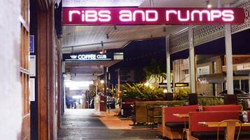 Ein Korridor mit Sitzbereichen und einem Neon-Schild mit der Aufschrift 'RIBS AND RUMPS'.