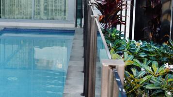 Ein Schwimmbecken mit Glasbarriere und Blumentöpfen.