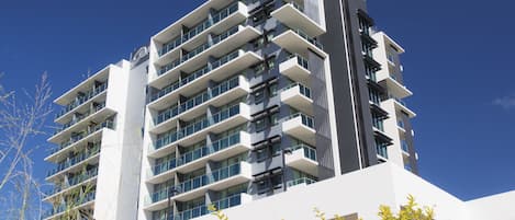 A modern multi-story building with balconies and large windows.