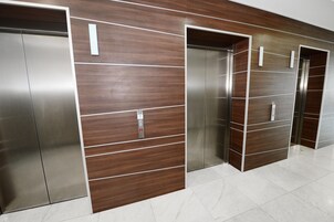 Una fila de ascensores con puertas metálicas y paneles de madera.