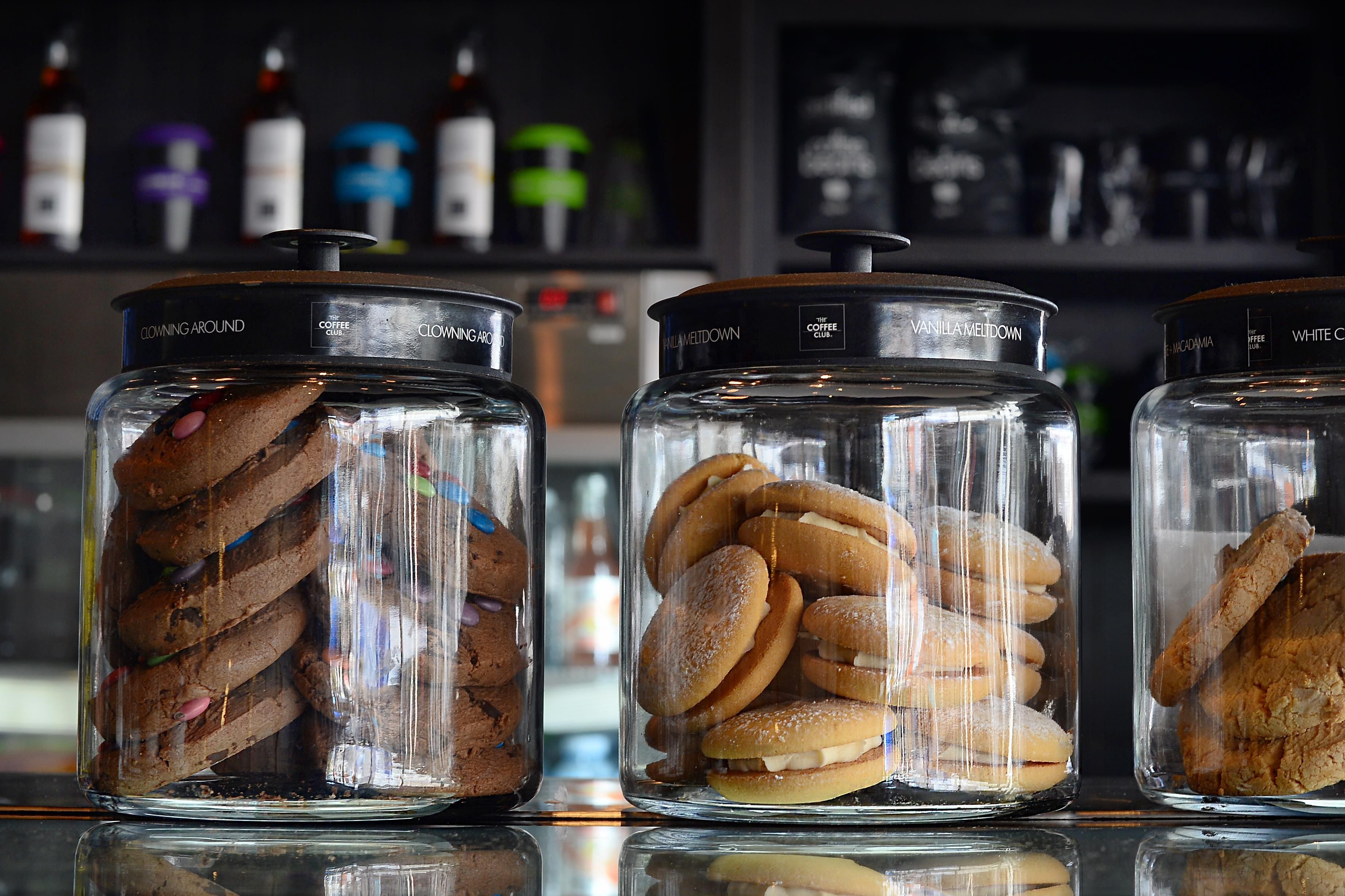Three glass jars with lids, each containing different types of cookies.