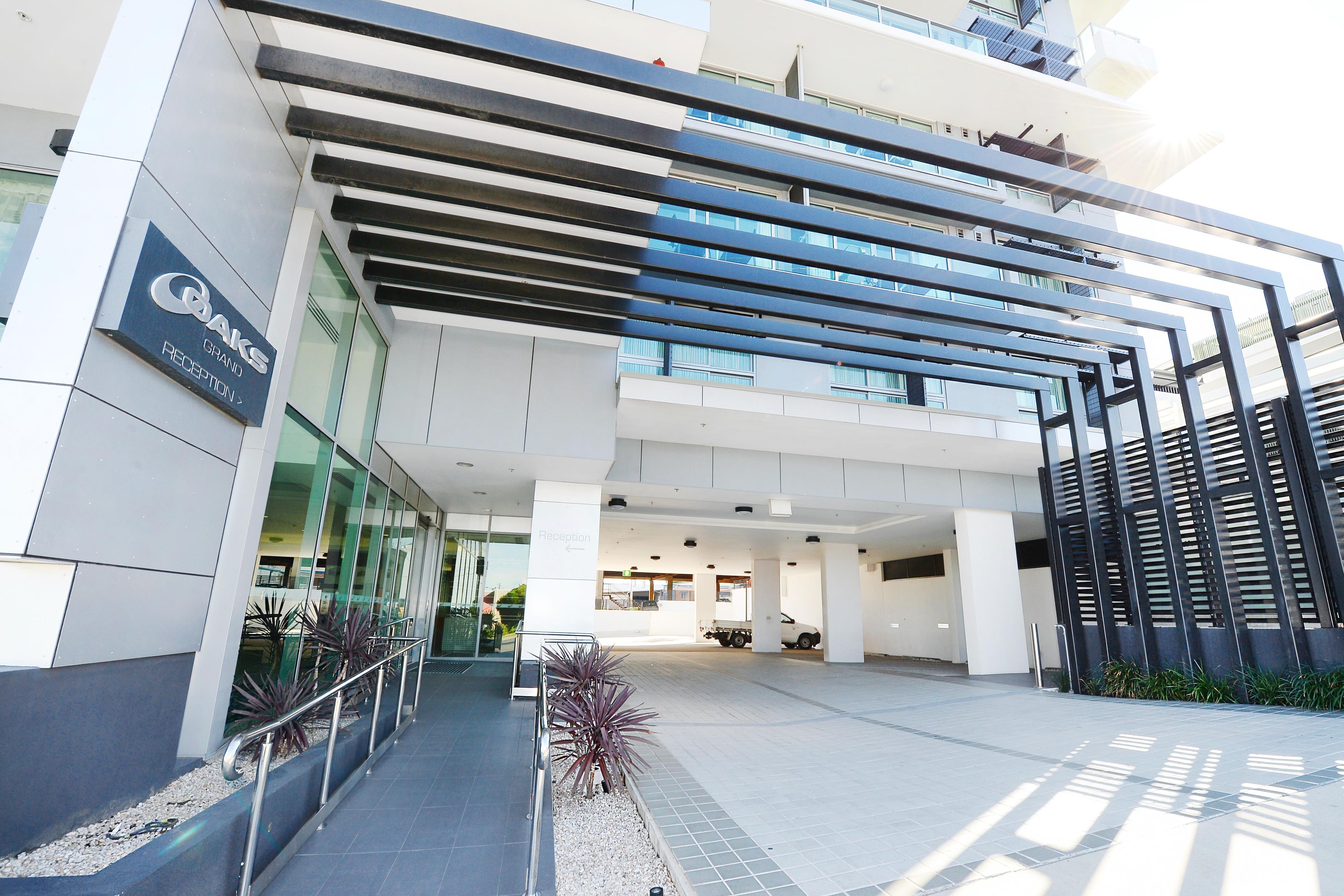 A modern building with a reception area, glass facade, and a parking lot.