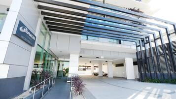 A modern building with a reception area, glass facade, and a parking lot.