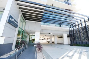 A modern building with a reception area, glass facade, and a parking lot. - Oaks Gladstone Grand Hotel (Gladstone)