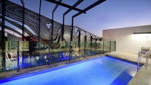 Une piscine intérieure dotée d’une structure moderne en verre et d’une ossature métallique.