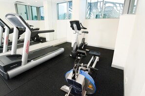 Un gimnasio con cinta de correr, elíptica y bicicleta estática.